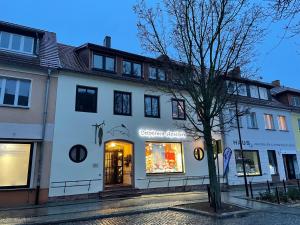 a white building with a store on a street at Haus Delphinen in Lübben