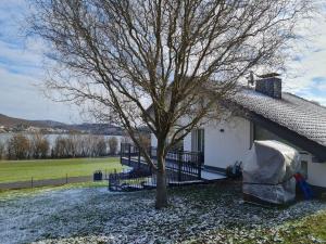 a tree in front of a house with snow on the ground at Haus Atlantis am Edersee in Bringhausen