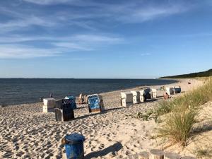 a beach with chairs and people sitting on the sand at Blaumuschel Haus A Wohnung 2 - DH in Lubmin +9 photos