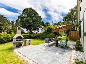 a patio with a table with an umbrella and a grill at Ferienwohnung im Spöckerhus in Tribohm