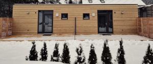 a wooden building with two doors in the snow at FREE Ride cabins in Tösens