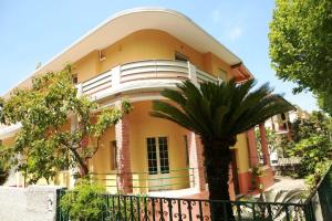 un bâtiment jaune avec un palmier devant lui dans l'établissement Appartamento Aurora, à Praia a Mare