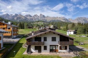 a house in a village with mountains in the background at Ciase Ai Ronch in Falcade