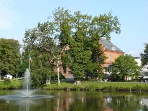 a fountain in the middle of a pond in front of a building at Klingl Ankerplatz Perle in Schönhagen
