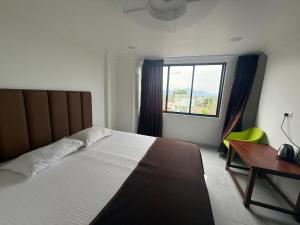 a bedroom with a bed and a desk and a window at Arlinjai Paradise in Kanyakumari