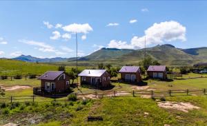 a group of houses in a field with mountains in the background at De Ark Mountain Lodge in Clarens +29 photos