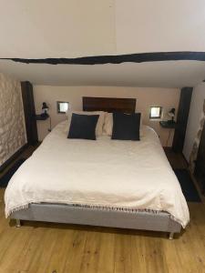 a bedroom with a large bed with black pillows at Ferme Fleurie in Bergesserin