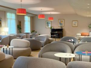 a waiting room with chairs and tables and a piano at Hotel Caesius Thermae & Spa Resort in Bardolino