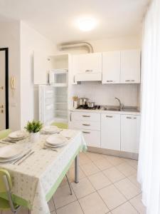 una cucina con mobili bianchi e un tavolo con dei piatti sopra di Residence Solemar - Agenzia Cocal a Caorle Altre 10 foto