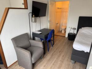 a room with a desk and a chair and a bedroom at Hotel Mayflower in Leiden