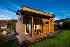 a small wooden cabin with a table on a deck at Ferienhaus Eifeltraum Magma in Berlingen +17 photos