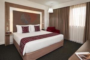 a hotel room with a large bed and a red chair at Accra City Hotel in Accra +46 photos