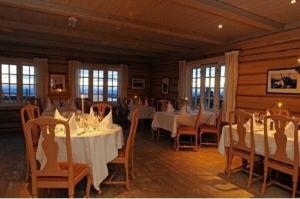 a dining room with white tables and chairs and windows at Hafjell apartment, Ilsetra in Øyer