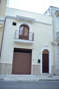 Biały budynek z dwoma drzwiami garażowymi i balkonem w obiekcie Appartamento Via Lata w mieście Brindisi