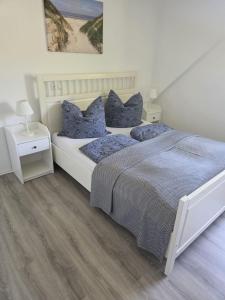 a white bedroom with a bed with blue pillows at Ferienwohnung Ahoi in Langwedel