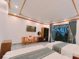 a bedroom with two beds and a table and a television at Tam Coc Cozy Hotel in Vũ Lâm +22 photos