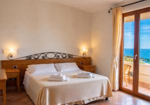 a bedroom with a bed with a view of the ocean at Hotel Villa Gustui Maris in Cala Gonone +75 photos