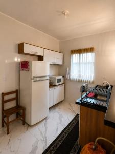a kitchen with a refrigerator and a chair in it at Beach House 96 in Itanhaém