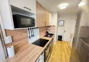 a kitchen with a sink and a tv on the wall at T5 cosy lumineux in Amiens