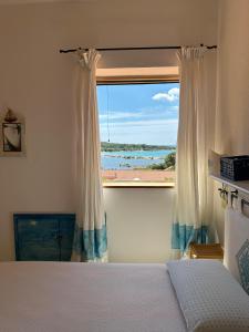 a bedroom with a bed and a window with a view at Residenze Coda Cavallo in San Teodoro
