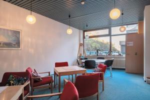 a waiting room with red chairs and tables and windows at Atelier Probst Schönwald in Aufʼm Bühl