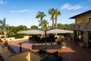 an outdoor patio with umbrellas and couches and palm trees at Baia Di Ulisse Wellness & Spa in San Leone