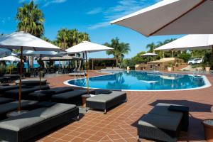 a swimming pool with lounge chairs and umbrellas at Baia Di Ulisse Wellness & Spa in San Leone
