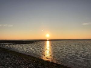 a sunset over the water with the sun in the sky at Ferienwohnung Komfort in Hakendorferwurp