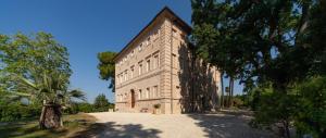 a large stone building with a palm tree in front of it at Borgo Storico Seghetti Panichi in Castel di Lama