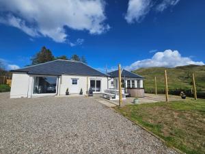 a white house with a gravel driveway at Penlarach House in Oban