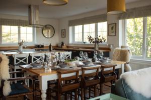 a dining room with a table and a kitchen with windows at Penlarach House in Oban