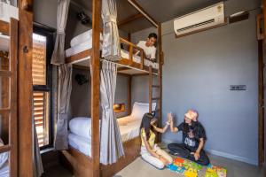 two people sitting on the floor in a room with bunk beds at Moustache Hostel Lonavala in Malavli