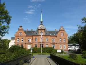a large red brick building with a clock tower at Klingl Ankerplatz Muschel in Schönhagen