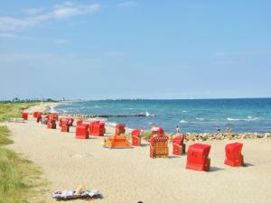 a beach with red chairs and people on the beach at Klingl Ankerplatz Muschel in Schönhagen