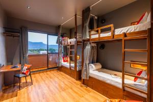 a dorm room with bunk beds with a desk and a window at Moustache Hostel Lonavala in Malavli +100 photos