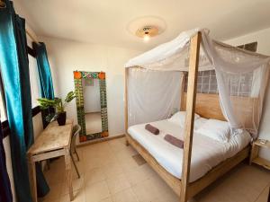 a bedroom with a canopy bed and a mirror at La Cabane du Pêcheur Atlantic Evasion in Dakar