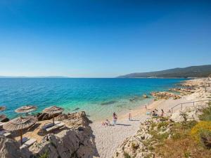 people on a beach with umbrellas and the ocean at Villa Fortuna - Private Pool and Garden Retreat in Labin