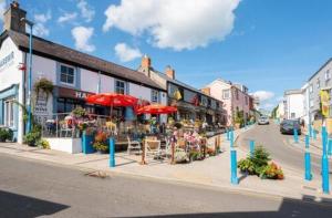 a street with tables and chairs and umbrellas on a city street at Affordable Saundersfoot Holidays in Pembrokeshire