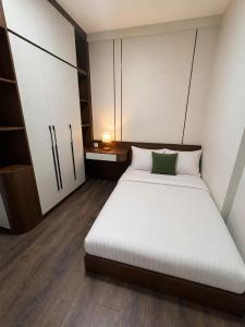 a bedroom with a white bed with a green pillow at Cara Riverside Cần Thơ- 2 mins GO Cần Thơ in Can Tho