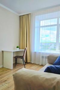 a living room with a desk and a window at Жк "AUEZOV" in Kokshetau +6 photos