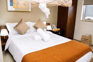 a bedroom with a bed with white sheets and pillows at AC Hotel in Luanda +5 photos