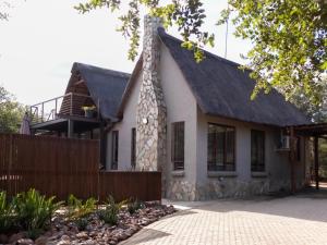 a house with a thatched roof and a fence at Ntoma House in Hoedspruit