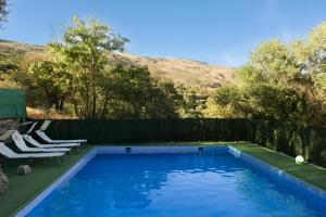 a swimming pool with two chairs and a fence at El Rincón de Muñoz - La Alpujarra in Yegen