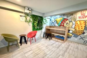 a room with chairs and a wall with a mural at Lazy Gibbon 1 Chiang Mai - Tha Phae Gate in Chiang Mai