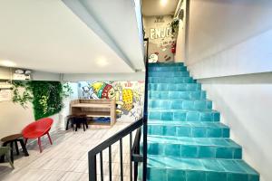 a staircase in a house with blue floors and a red chair at Lazy Gibbon 1 Chiang Mai - Tha Phae Gate in Chiang Mai