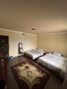 two beds in a room with a rug on the floor at Subhechchha Hotel in Charikot