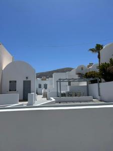 a view of a white building with a palm tree at Tarelis Beach Apartments & Studios in Kamari