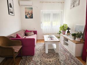 a living room with a purple couch and a table at Apartman ODISEJ in Čapljina
