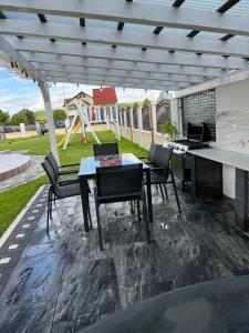 eine Terrasse mit Tisch und Stühlen unter einer Pergola in der Unterkunft Vila MEM in Sebeş