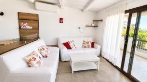 a living room with two white couches and a table at Rena Bianca Residence 201 in Baja Sardinia